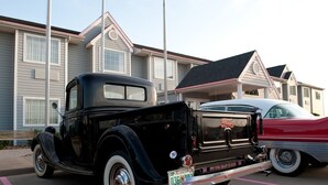 A vintage black pickup truck parked in a lot with a house in the background. - Motel 6 McAlester, OK - South (McAlester)