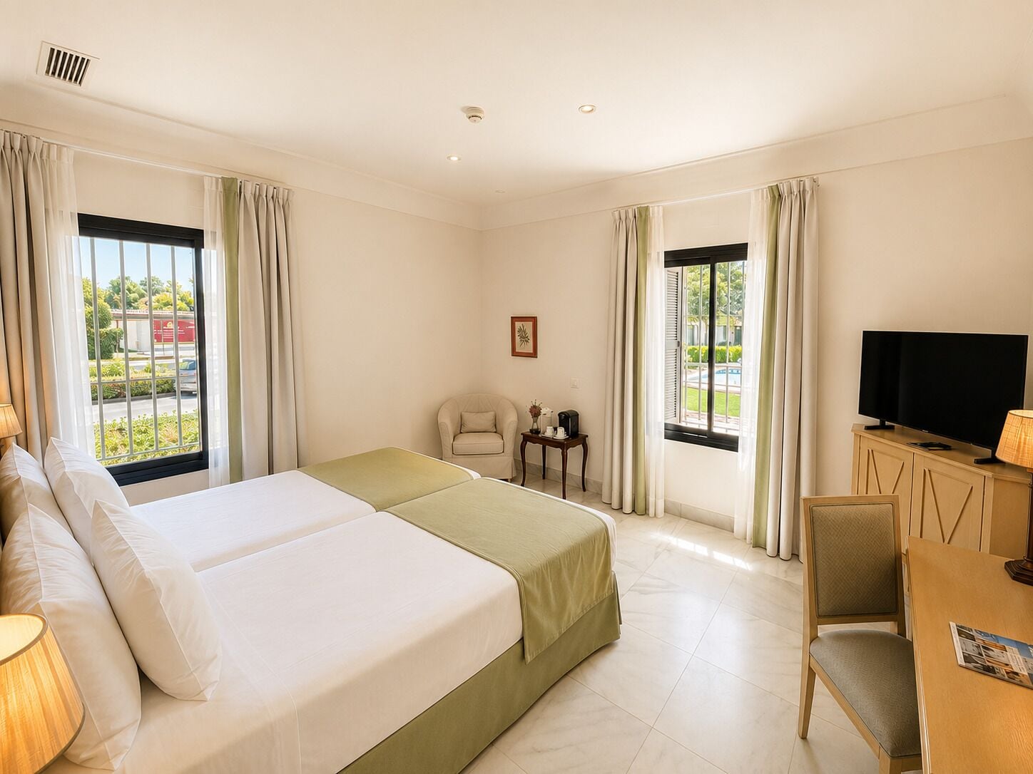 Una habitación de hotel con dos camas, televisión, escritorio y una silla.