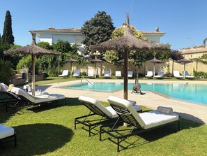 Una piscina al aire libre, sillones reclinables de piscina