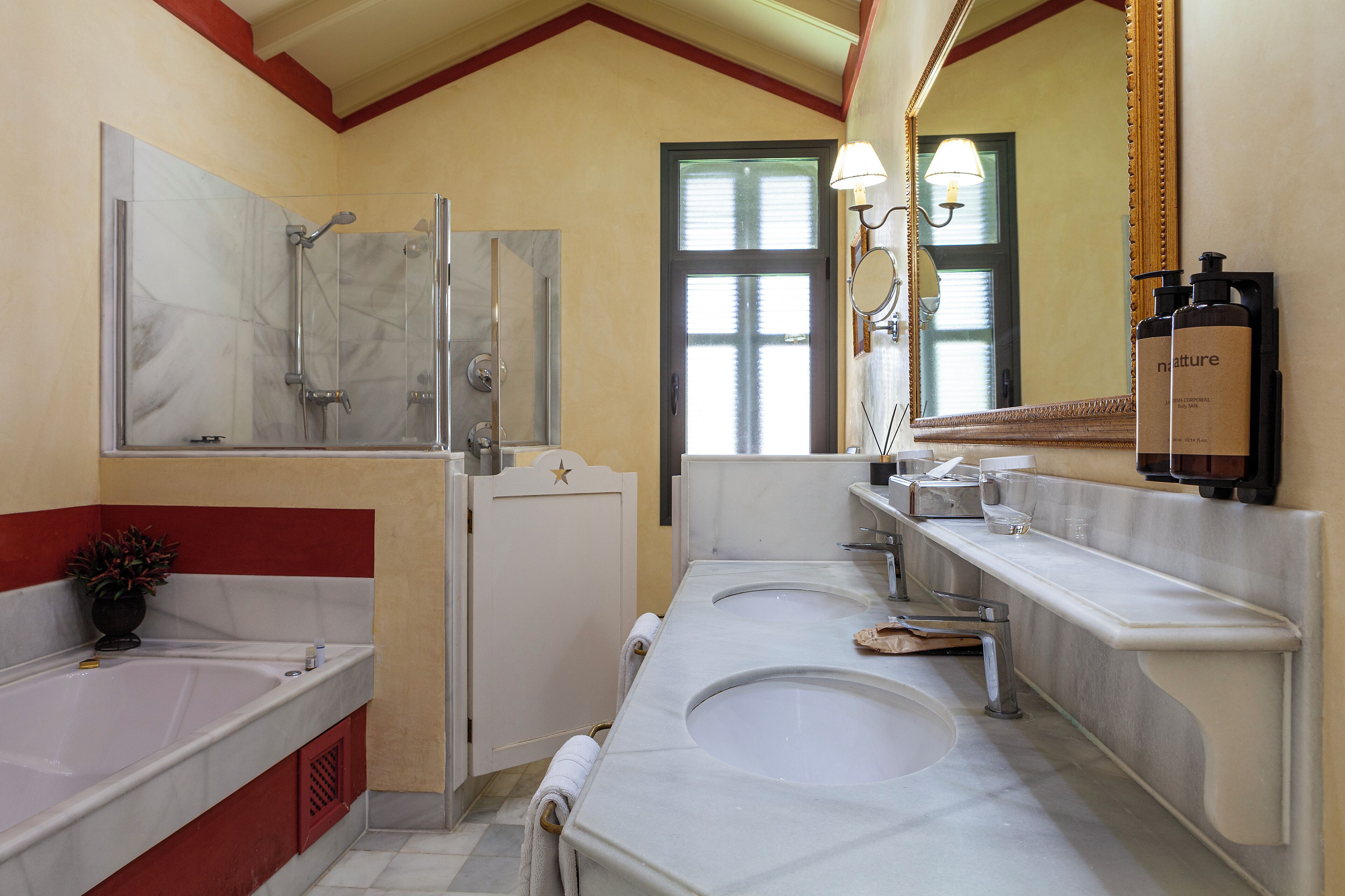Een badkamer met twee wastafels, een douche en een spiegel.
