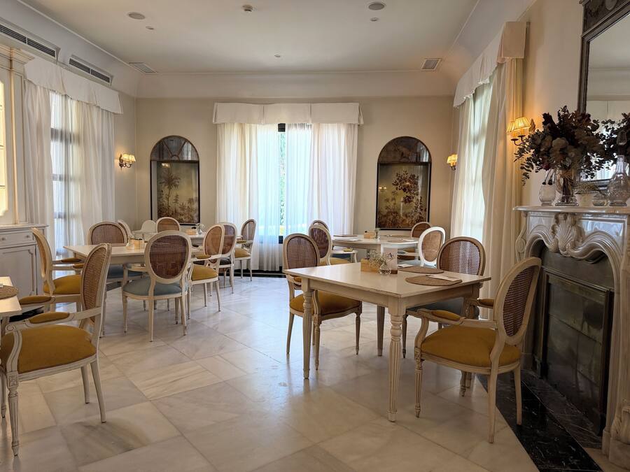 A dining area with round tables and wicker chairs, a fireplace, and a large mirror.