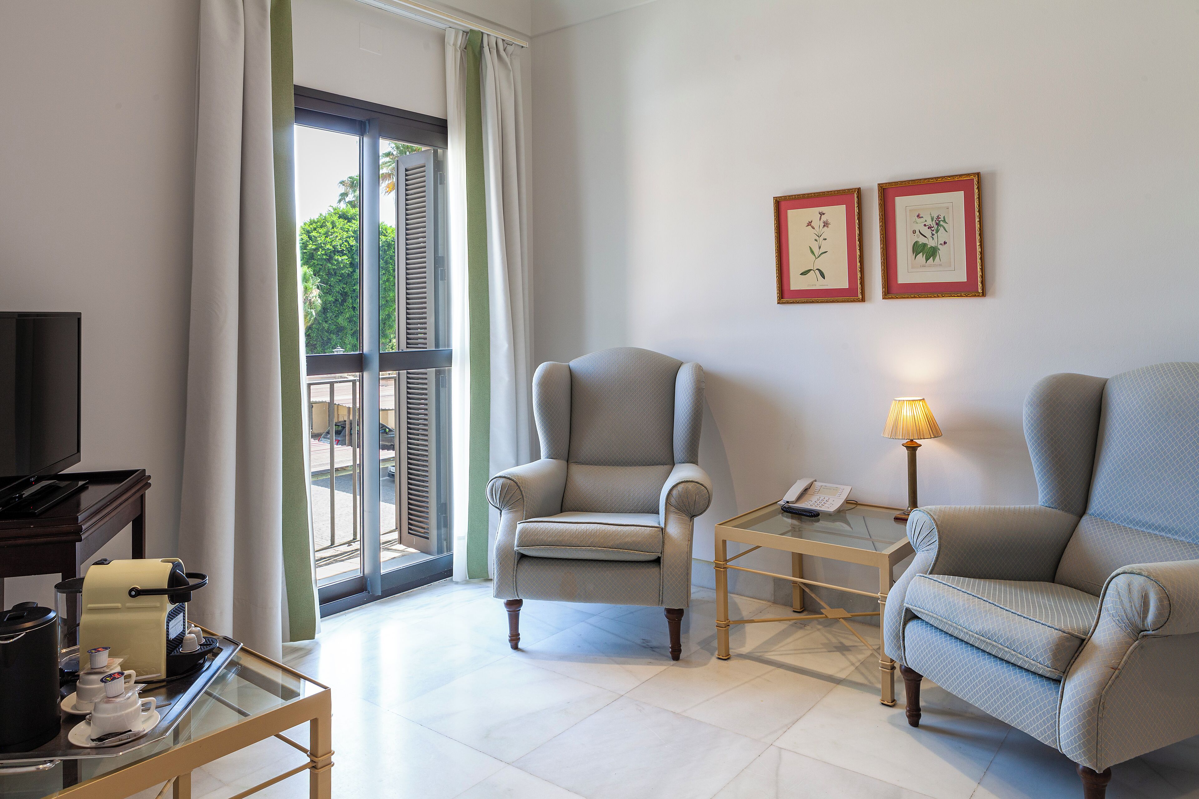 Una sala de estar con dos sillones, una mesa de centro, un televisor y un ventanal con cortinas.