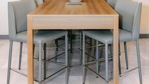 Une table à manger avec six chaises, un saladier de pommes vertes et un téléviseur à écran plat fixé au mur.