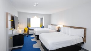 Une chambre d’hôtel avec deux lits, un bureau, une chaise et une fenêtre avec des rideaux.