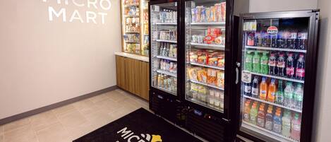 A MicroMart vending area with various beverage and snack options, a wooden ceiling, and a black floor mat with the MicroMart logo.