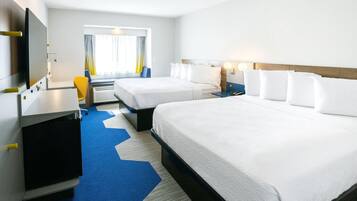 Quarto de hotel com duas camas, uma escrivaninha, uma cadeira e uma televisão.