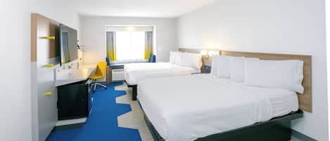Une chambre d’hôtel avec deux lits, un bureau, une chaise, un miroir et une fenêtre avec des rideaux.