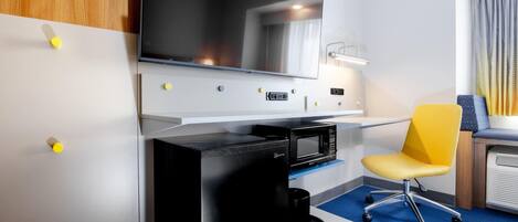 Une chambre d’hôtel moderne équipée d’un téléviseur à écran plat, d’une machine à café, d’un fauteuil jaune et d’un bureau.