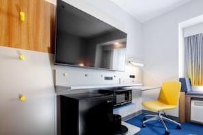 A modern hotel room with a flat-screen TV, a coffee maker, a yellow chair, and a desk. - Microtel Inn & Suites by Wyndham Wellsville (Wellsville)