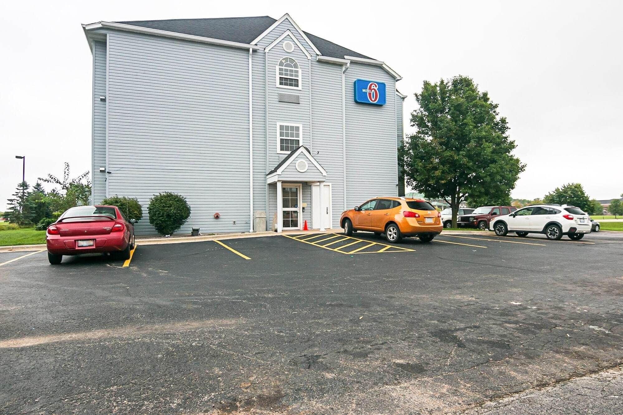A motel with a large parking lot, a single-story building, and a sign indicating it is a Motel 6.