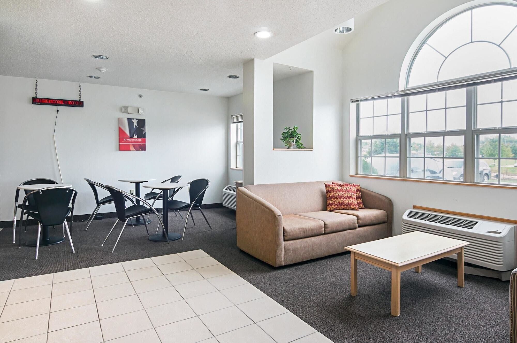 A modern office space with a beige sofa, a small table, and a dining area with chairs.