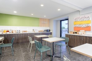 A modern kitchen with wooden cabinets, a green accent wall, and a countertop with various appliances and items.
