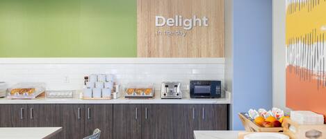 A modern kitchen with a wooden cabinet, a microwave, and a toaster. There is a sign that reads "Delight in the day" on the wall.