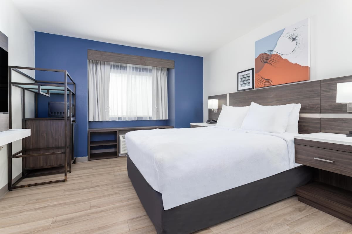 Una habitación de hotel moderna con una cama grande, un escritorio y una ventana con cortinas.