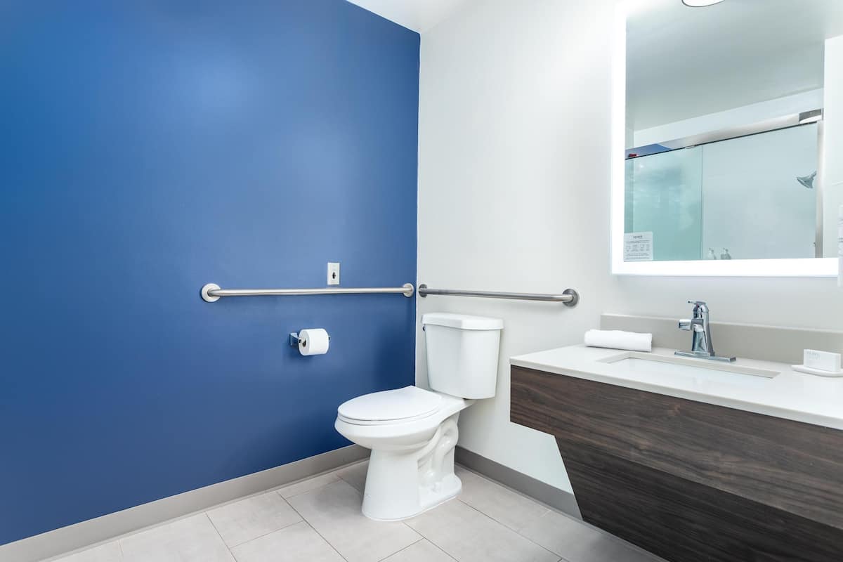 Un baño moderno con pared azul, inodoro blanco y tocador con espejo.