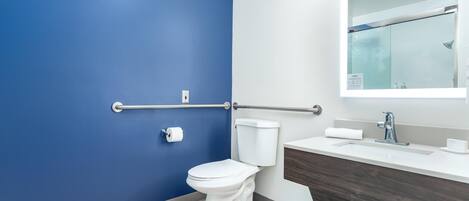 Une salle de bain moderne avec un mur bleu, des toilettes blanches et un meuble-lavabo avec un miroir.