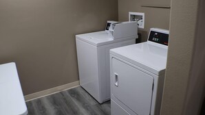 A laundry room with two white washing machines and a small table. - Sleep Inn Marion - Cedar Rapids (Marion)