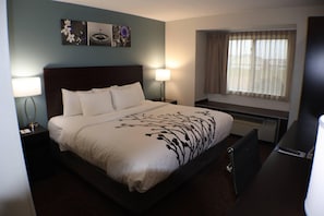 A hotel room with a bed, two bedside lamps, a window with curtains, and a wall-mounted artwork. - Sleep Inn Marion - Cedar Rapids (Marion)