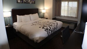 A hotel room with a large bed, two bedside lamps, a window with curtains, and a flat-screen TV. - Sleep Inn Marion - Cedar Rapids (Marion)