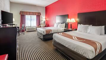 A hotel room with two beds, a TV, a desk, and a chair.