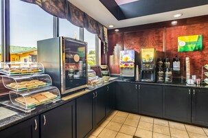 A breakfast bar with a coffee machine, juice dispenser, and various food items.