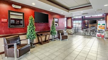 A restaurant interior with a red wall, a large TV, and a menu board.