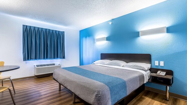 A hotel room with a bed, bedside table, and a small table with chairs.