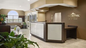 A reception area with a modern design, featuring a reception desk, seating area, and a large window providing natural light. - Microtel Inn & Suites by Wyndham Cambridge (Cambridge)