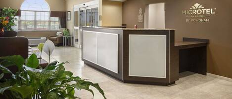 A reception area with a modern design, featuring a reception desk, seating area, and a large window providing natural light.