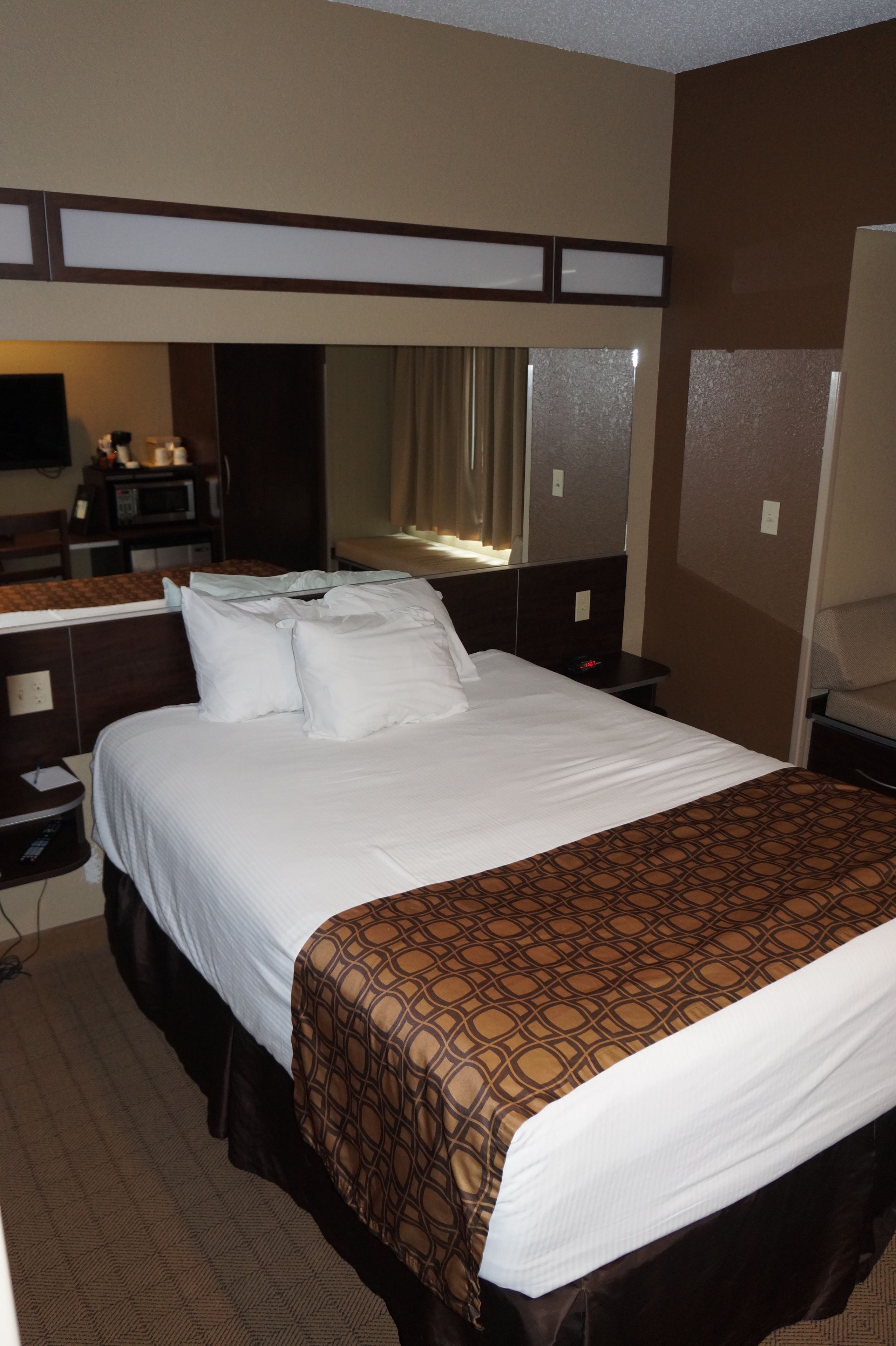 A hotel room with a large bed, a desk, a chair, a television, and a bathroom.