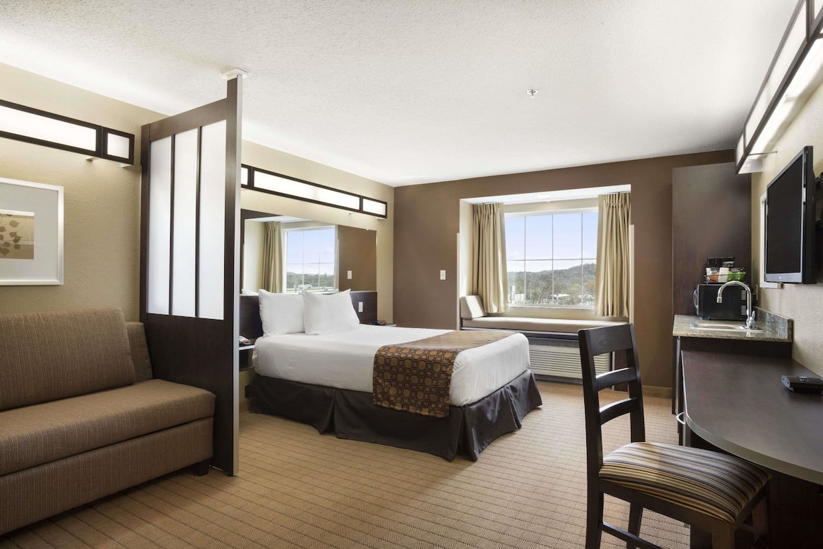 A hotel room with a bed, a sofa, a desk, and a window with a view.