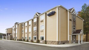 A Microtel by Wyndham hotel with a multi-story exterior, a parking lot, and a clear sky. - Microtel Inn & Suites by Wyndham Cambridge (Cambridge)