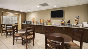 A hotel room with a kitchenette, a flat-screen TV mounted on the wall, and a dining area with chairs and a table. - Microtel Inn & Suites by Wyndham Cambridge (Cambridge)
