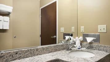 A bathroom with a granite countertop sink, a mirror, and a towel rack with folded towels.