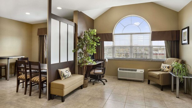 A hotel room with a dining area, a sofa, a desk, and a large window with a view. - Microtel Inn & Suites by Wyndham Cambridge (Cambridge)
