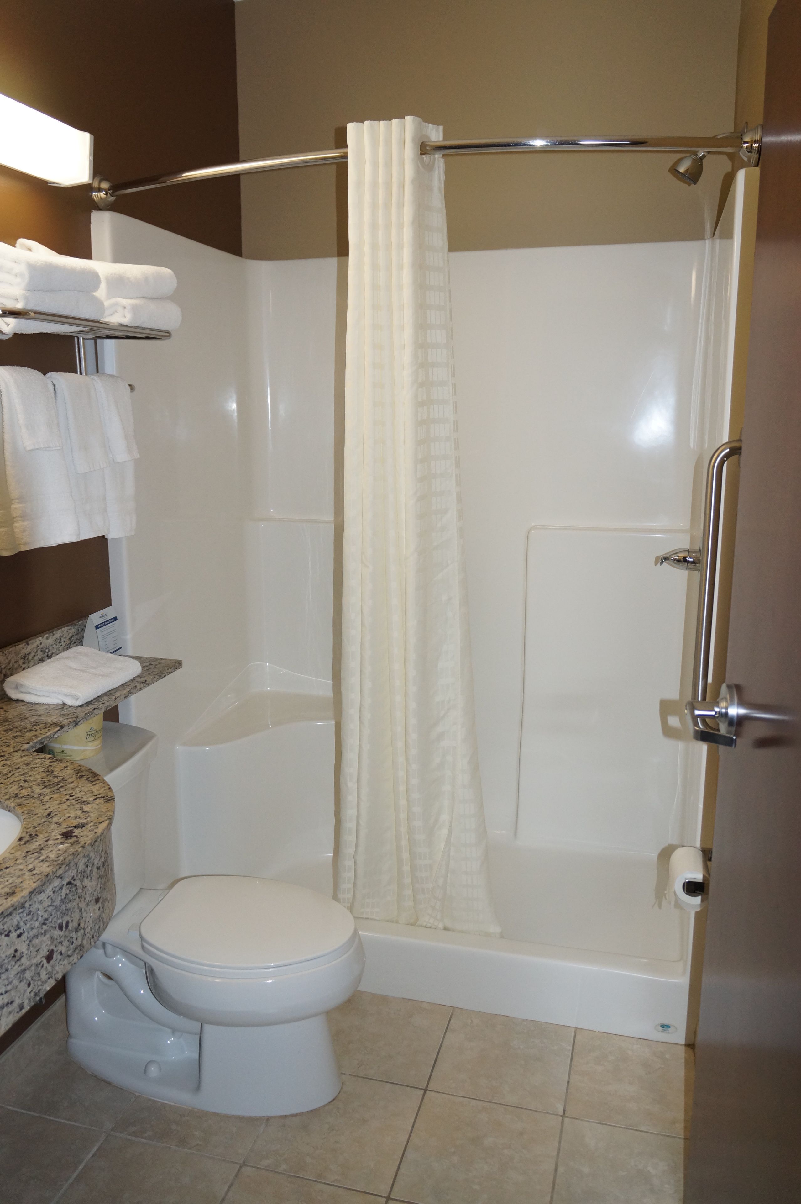 A bathroom with a toilet, a shower with a glass door, and a vanity with a sink and towel rack.
