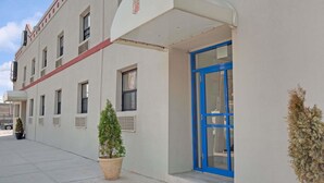 A building with a white facade, a blue door, and a small potted plant in front. - Super 8 by Wyndham Long Island City LGA Hotel (Astoria)