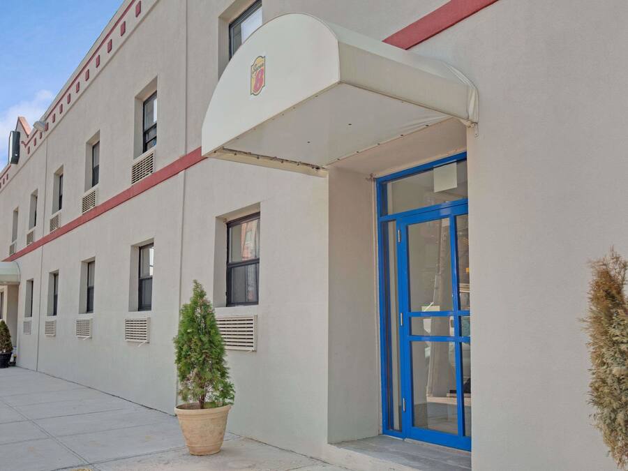 Un bâtiment à la façade blanche, avec une porte bleue et une petite plante en pot devant l’entrée.