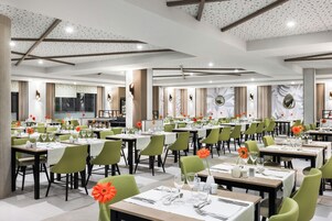 A spacious dining area with multiple tables and chairs, well-lit with ceiling lights, and adorned with wall art and decorative elements.