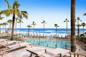 Una piscina techada, una piscina al aire libre, sombrillas