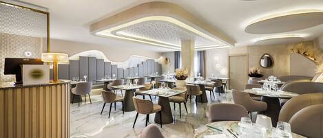 A modern dining area with round tables, chairs, and a reception desk.