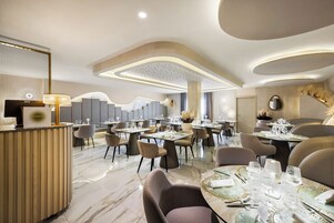 A modern dining area with round tables, chairs, and a reception desk.