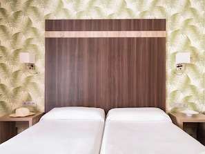 A hotel room with two beds, a wooden headboard, and a tropical leaf pattern on the walls. - Hotel Ona Diana Park (Estepona)