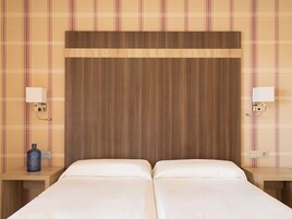 Een tweepersoonsbed met houten hoofdeinde in een hotelkamer.