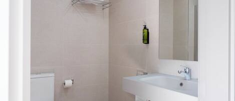 A bathroom with a toilet, a sink, a mirror, and a towel rack.