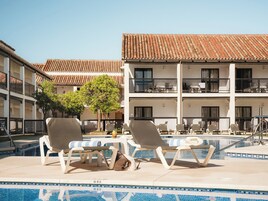 Una piscina al aire libre, sombrillas, tumbonas