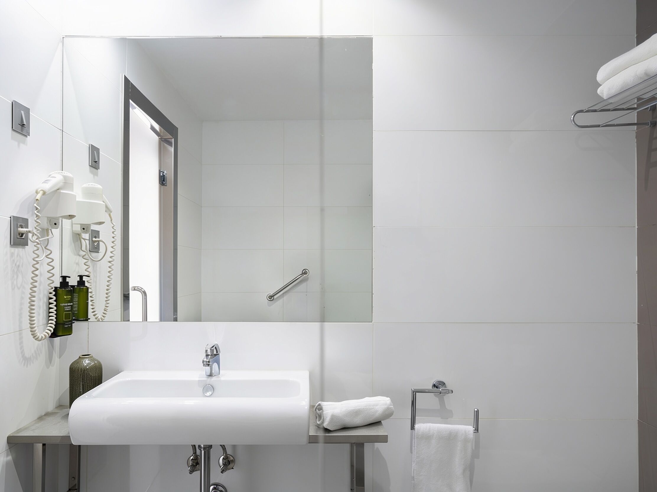 A modern bathroom with a large mirror, a sink, and a shower area.