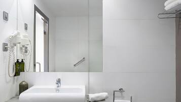 Un baño moderno con un espejo grande, un lavamanos y una zona de ducha.