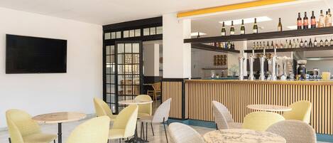 A modern bar area with multiple seating options and a variety of bottles on the shelves.