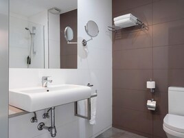 Un baño moderno con un lavabo blanco, un espejo, toallero, inodoro y ducha.